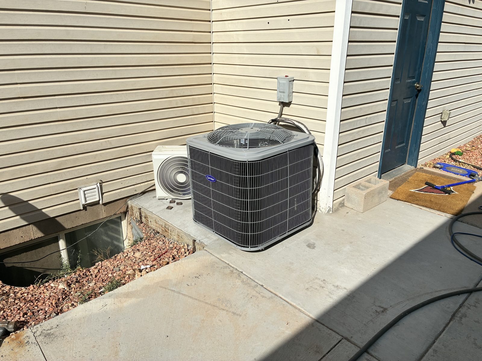 Carrier air conditioning condenser and ductless mini-split unit installed beside a Southern Utah home